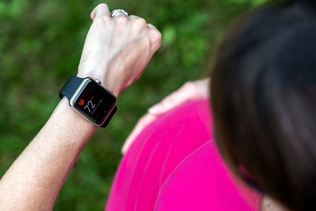 A woman glances down at her Apple Watch, a  wearable tech solution that can show real-time health metrics like heart rate.