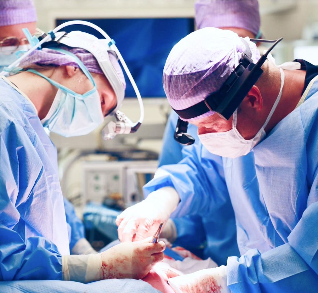 Surgeons operating on a patient using Rods and Cones medical tech glasses.