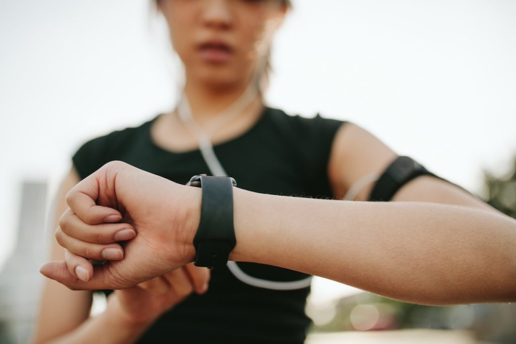 A close-up shot of a young woman in fitness gear checking her wearable tech smartwatch. 