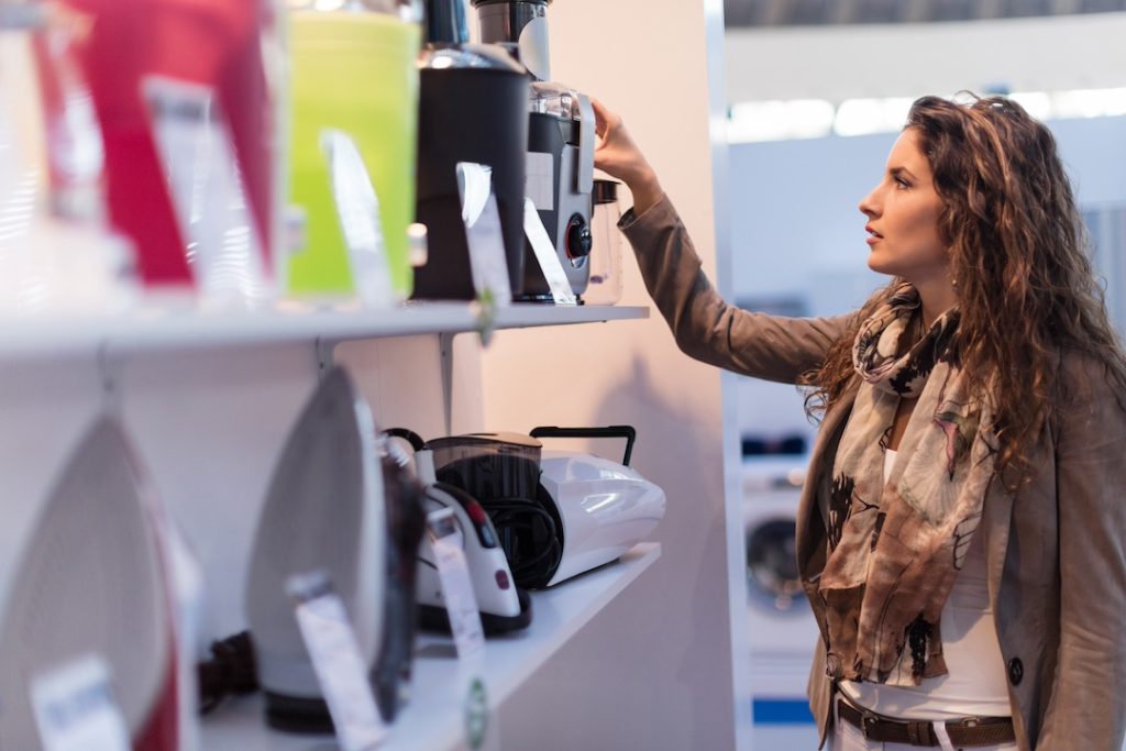 An image of a woman inspecting several appliances on a store shelf representing how eco-conscious consumers pay attention to sustainability.